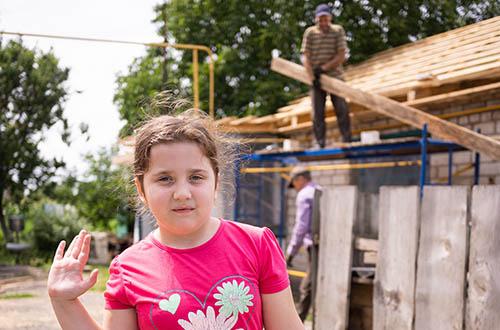 Happy child on background rebuilding roof destroyed by Russians